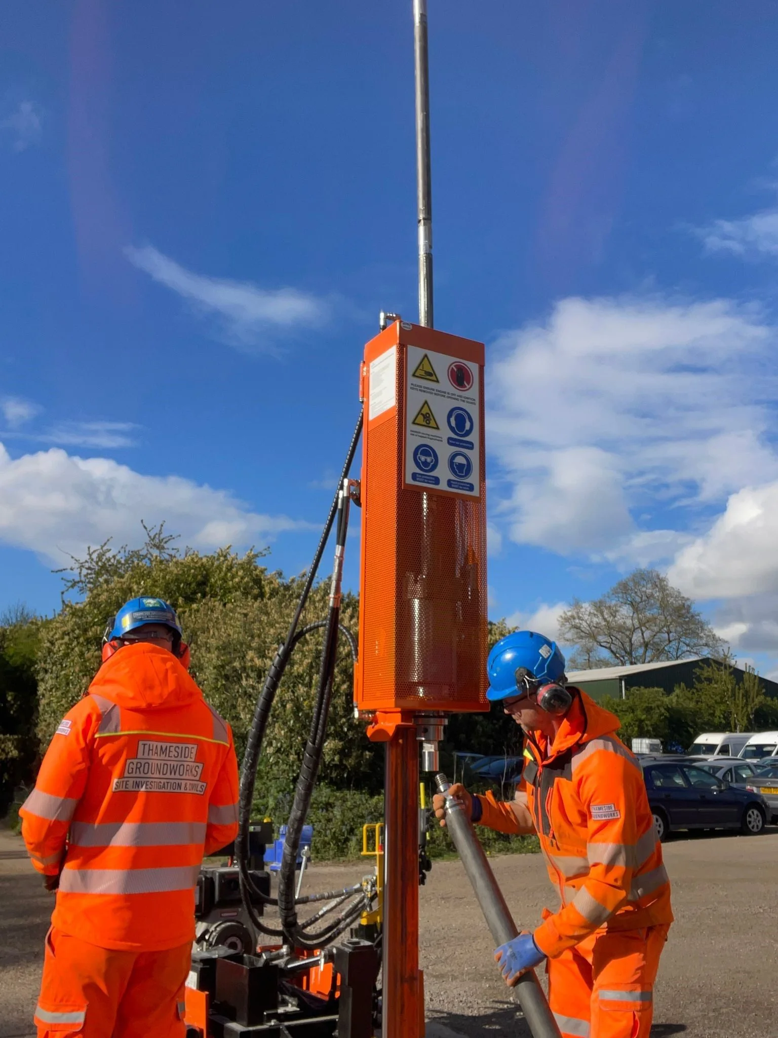 Drilling rods extending vertically into a clear blue sky during a deep sampling run.